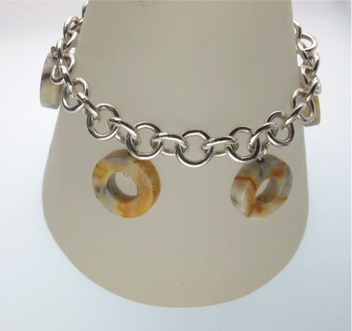 Banded agate washer shapes hanging from sterling silver chain bracelet shown on stand