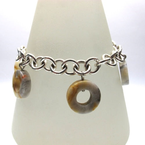 Banded agate washer shapes hanging from sterling silver chain bracelet shown on stand side view