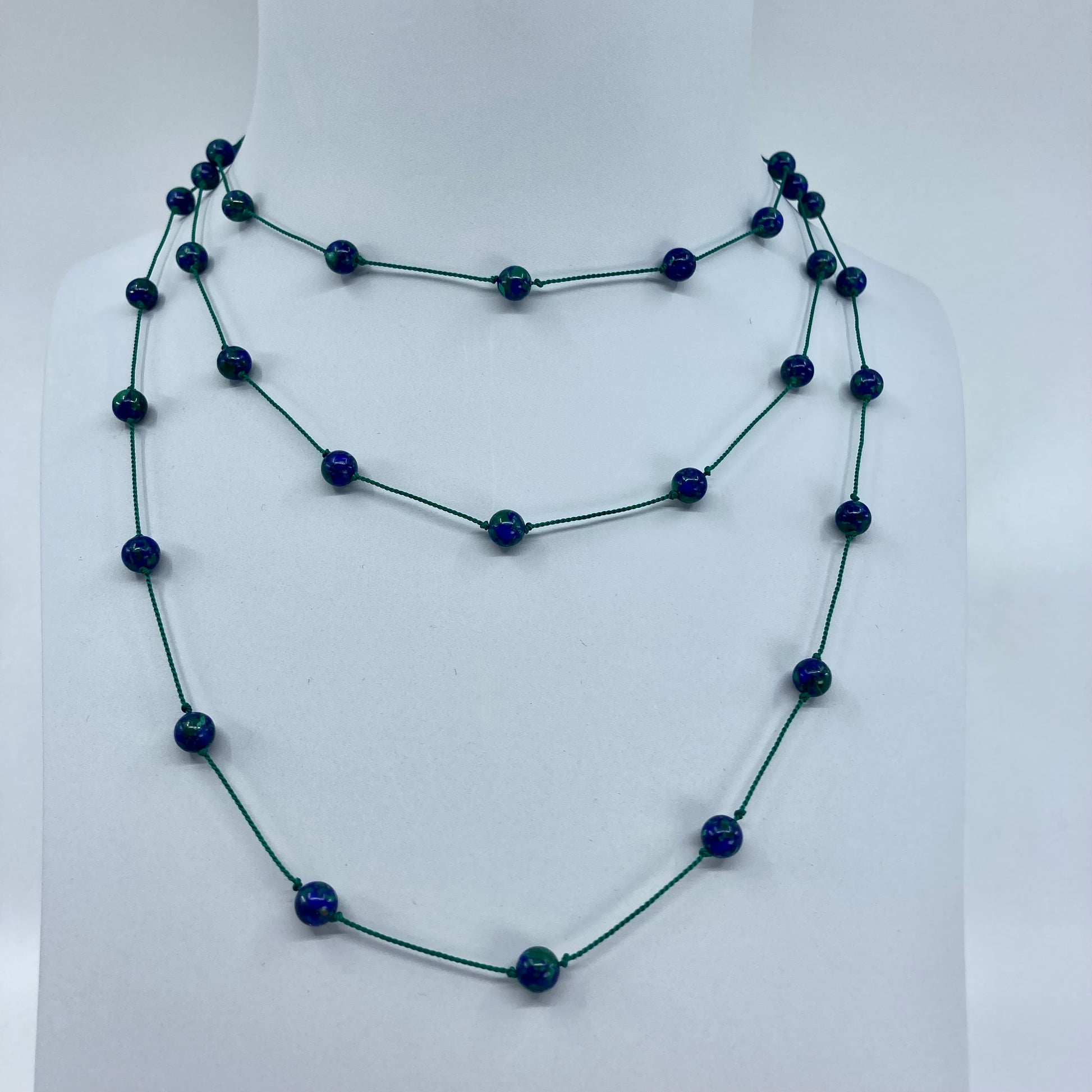 Azurmalachite beads threaded and spaced out on silk cord with sterling silver clasp tripled over display bust